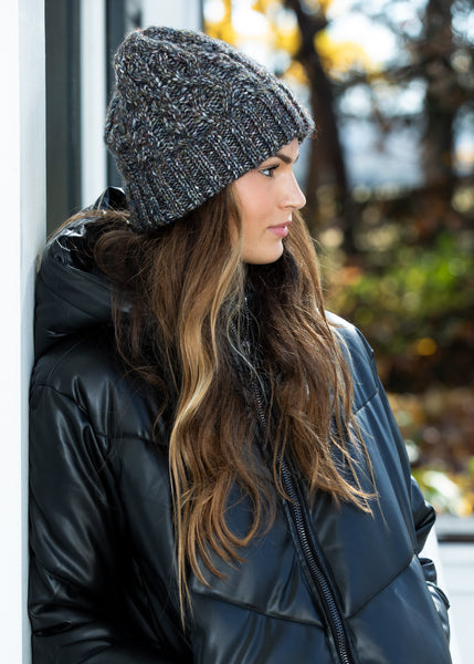 Woman wearing Adeline Beanie Black with a cozy black  winter coat, looking effortlessly chic.