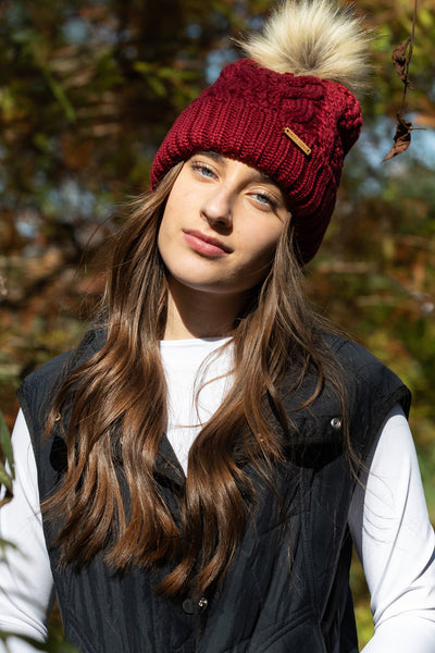 Woman wearing Eco-Spurr Beanie in Burgundy with Faux Fur pom-pom and fleece fold-over cuff, made from recyclable Pollyanna fiber.
