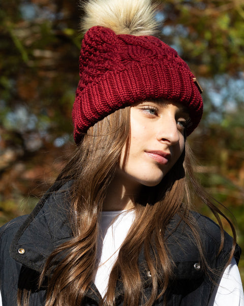 Woman wearing burgundy Eco-Spurr Beanie with Faux Fur pom-pom in an outdoor setting
